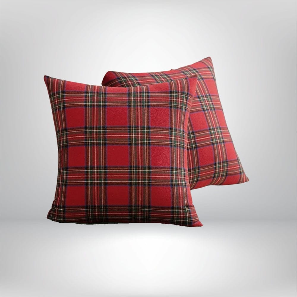 Housse de coussin décoratif à motif tartan rouge et noir, posée sur un canapé moderne