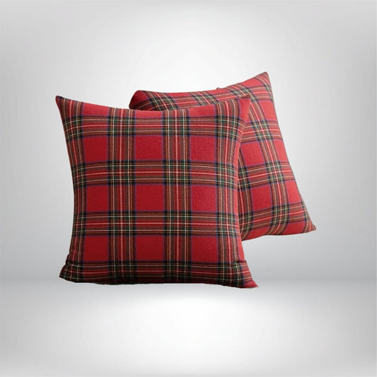 Housse de coussin décoratif à motif tartan rouge et noir, posée sur un canapé moderne