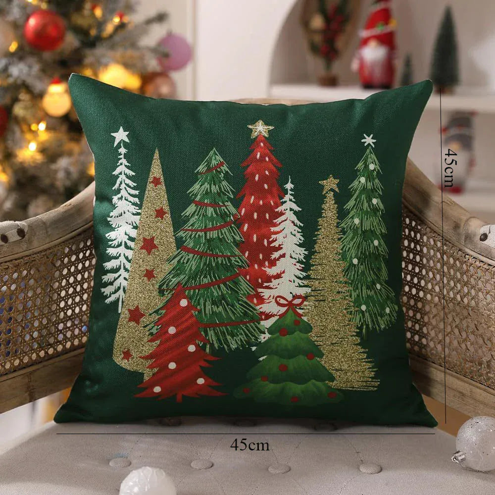 Housse de coussin décoratif vert avec motifs d'arbres de Noël rouges et dorés sur un canapé en rotin
