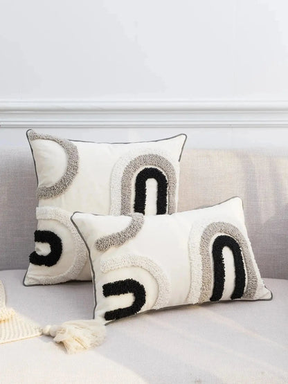 Housse de coussin décoratif aux motifs abstraits noir, blanc et gris sur un canapé moderne