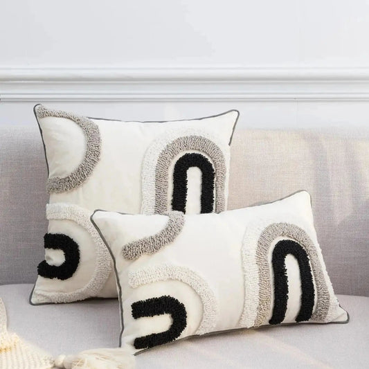 Housse de coussin décoratif aux motifs abstraits noir, blanc et gris sur un canapé moderne