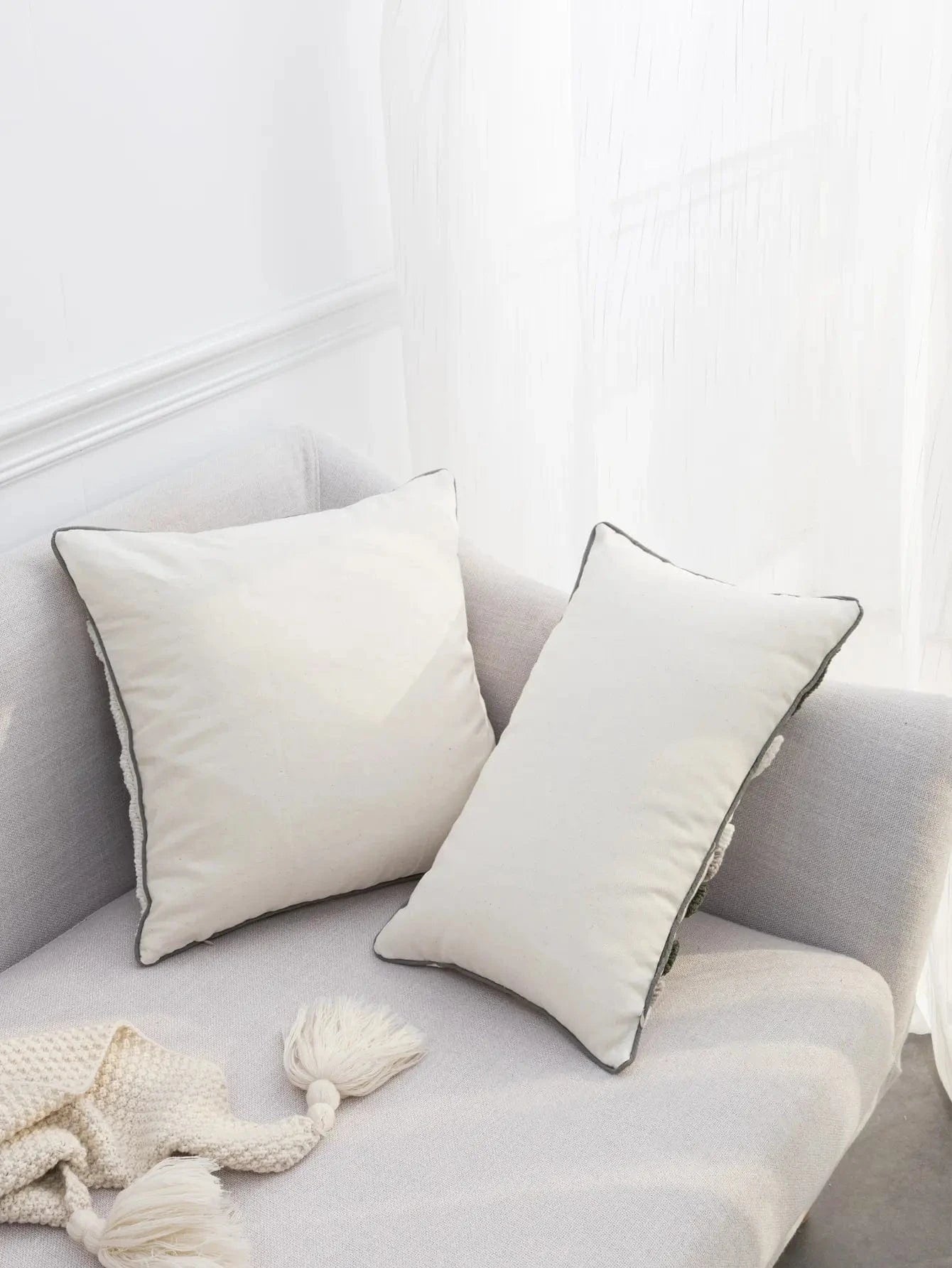 Coussins décoratifs en lin beige sur un canapé moderne, avec un design épuré et des bordures contrastantes