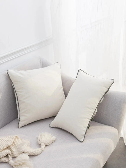 Coussins décoratifs en lin beige sur un canapé moderne, avec un design épuré et des bordures contrastantes