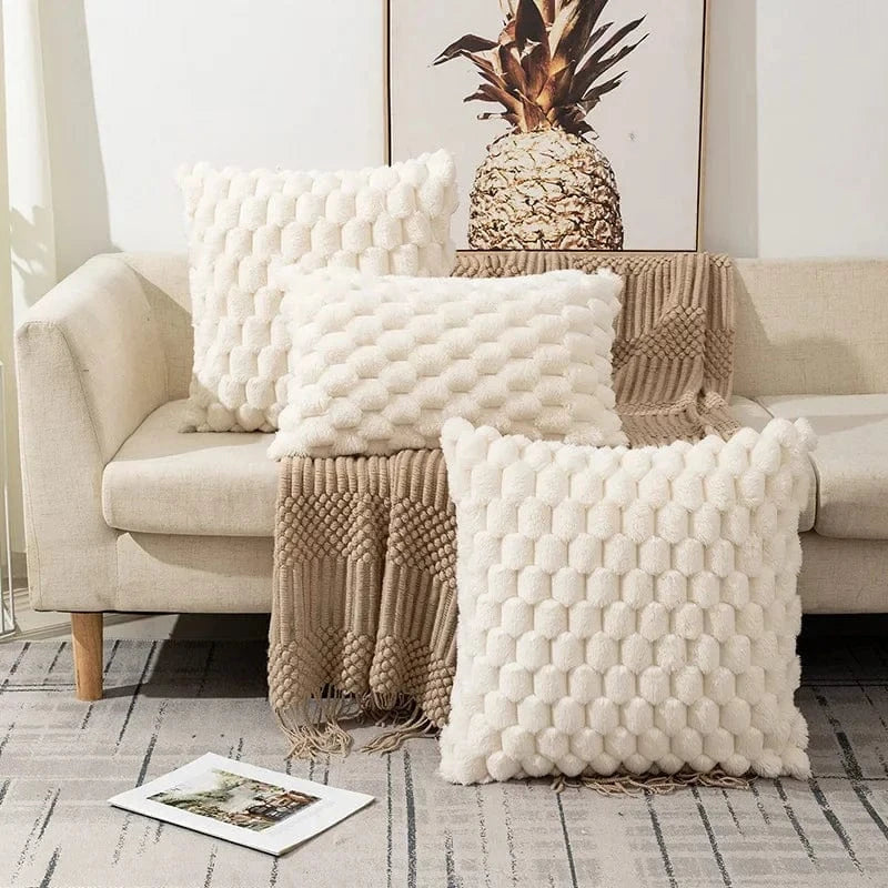 Coussins décoratifs en fausse fourrure beige sur un canapé, ajoutant élégance et douceur à votre intérieur