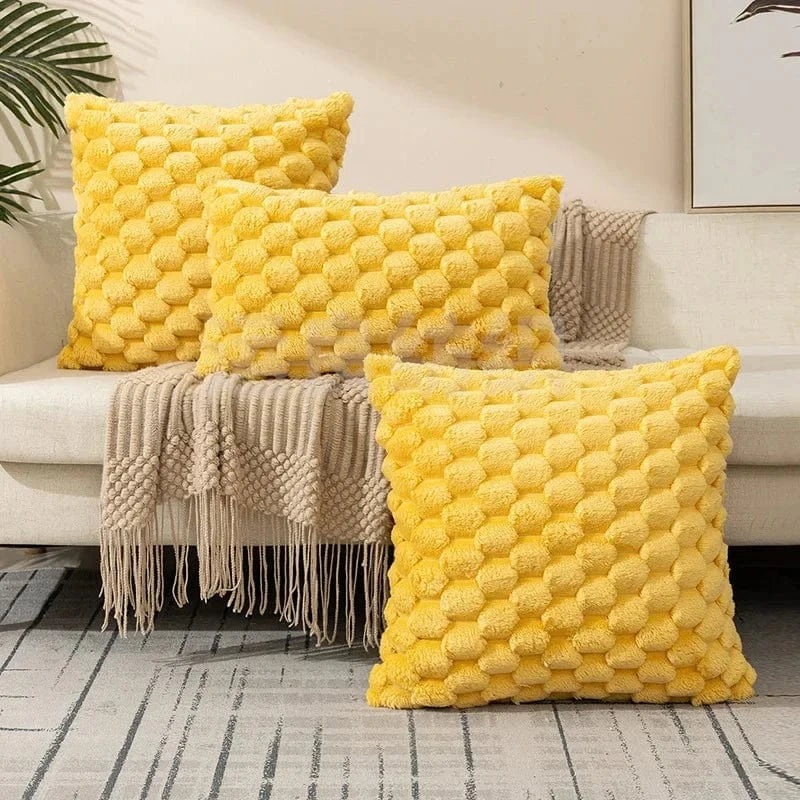 Coussins décoratifs jaunes en forme de carré avec texture douce, posés sur un canapé clair et un plaid