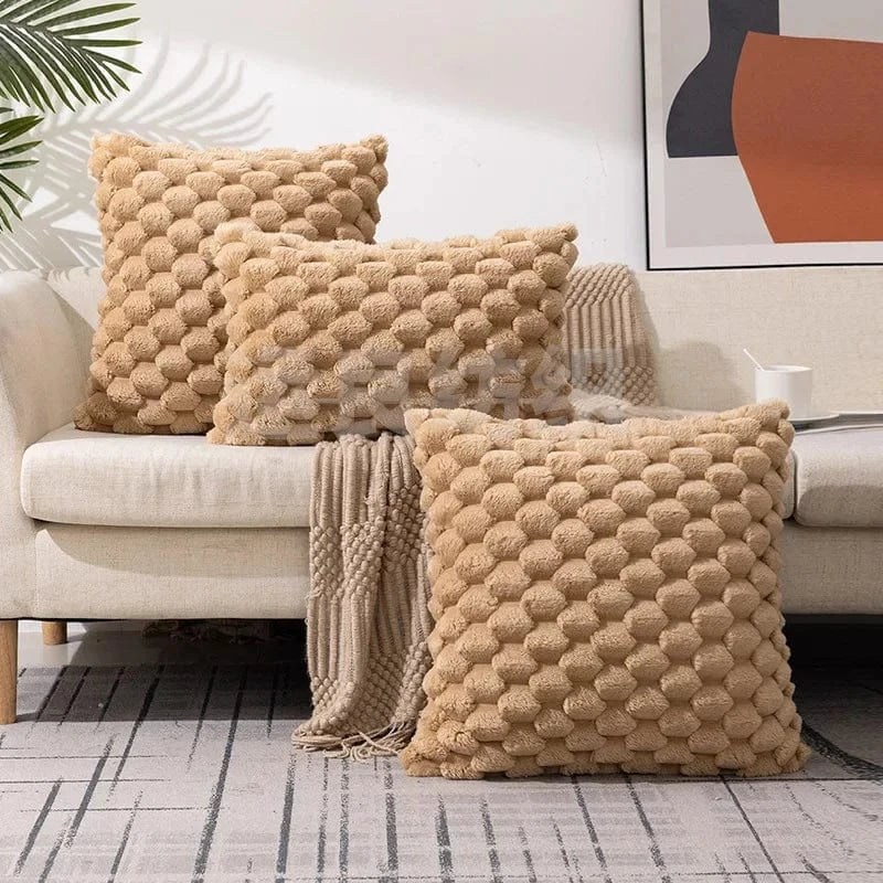 Coussins décoratifs en matière douce, couleur beige, avec un motif texturé, sur un canapé moderne