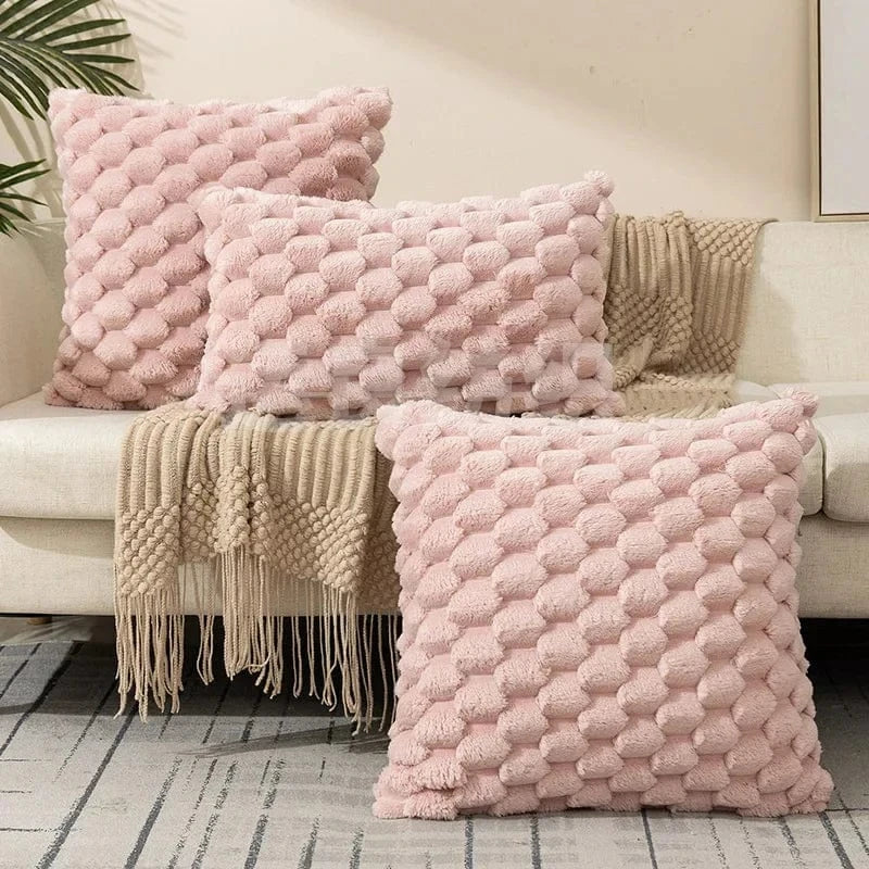 Coussins décoratifs rose en tissu doux avec un motif texturé, disposés sur un canapé clair dans un salon moderne