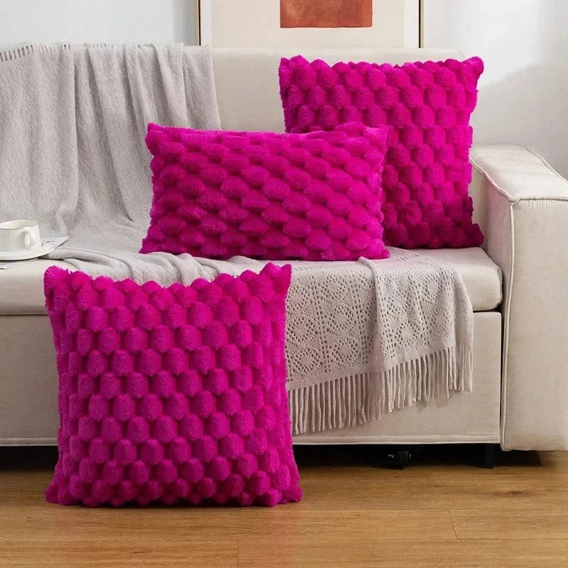 Coussins décoratifs en velours fuchsia avec motifs texturés, posés sur un canapé clair dans un salon moderne