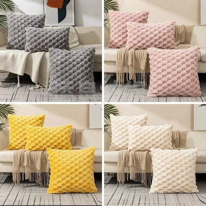 Coussins décoratifs aux textures douces et colorées, disposés sur un canapé avec un plaid beige