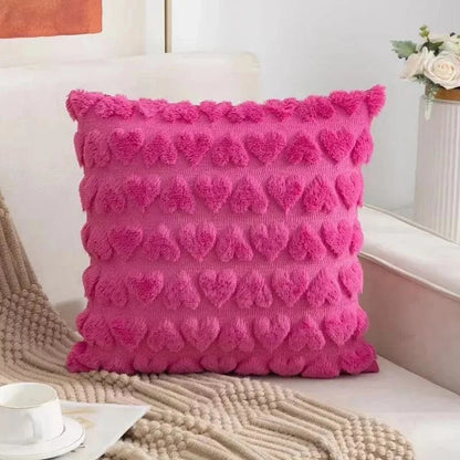 Coussin décoratif rose en velours avec motifs en forme de cœur, posé sur un canapé doux et élégant