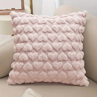 Coussin décoratif rose en velours avec motifs en forme de cœurs, posé sur un canapé beige