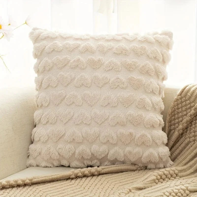 Coussin décoratif beige en forme carrée avec motifs en relief sur un canapé clair, apportant une touche chaleureuse