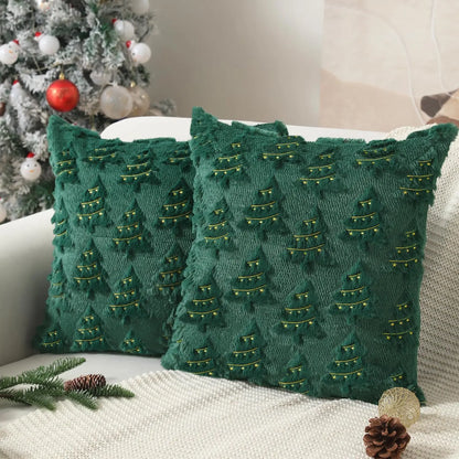 Housse de coussin verte avec motifs de sapins dorés, posée sur un canapé dans un salon décoré pour Noël