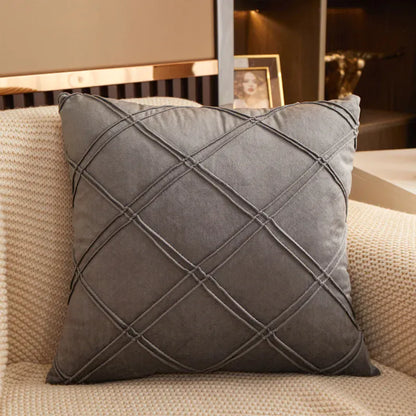 Coussin déco en velours gris avec motif losanges, posé sur un canapé beige texturé dans un salon élégant