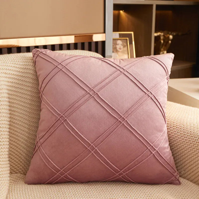 Coussin décoratif en velours rose avec motif en losanges, posé sur un fauteuil beige dans un salon moderne