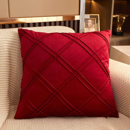 Coussin décoratif en velours rouge avec motif en losanges, posé sur un canapé beige dans un salon moderne
