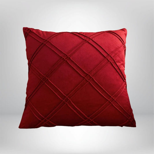 Coussin décoratif en velours rouge avec un motif en losanges, posé sur un fond neutre