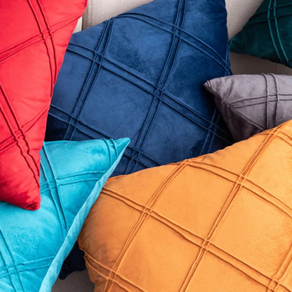 Coussins décoratifs en velours aux couleurs vives, avec motifs géométriques, disposés sur un canapé moderne