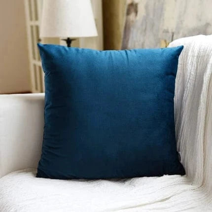 Coussin déco en velours bleu profond posé sur un canapé blanc, ajoutant une touche d'élégance à la décoration