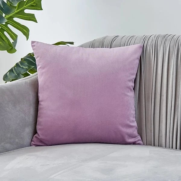 Coussin déco en velours rose posé sur un canapé gris, ajoutant une touche d'élégance à la pièce