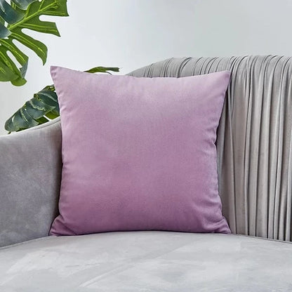 Coussin déco en velours rose posé sur un canapé gris, ajoutant une touche d'élégance à la pièce