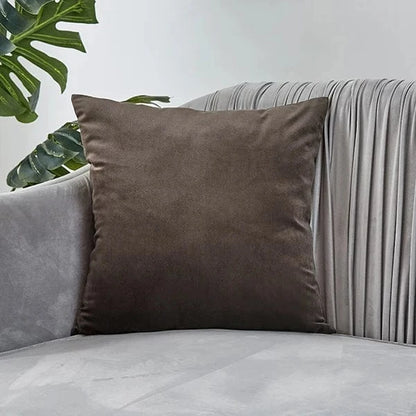 Coussin déco en velours marron posé sur un canapé gris, ajoutant élégance et douceur à l'espace