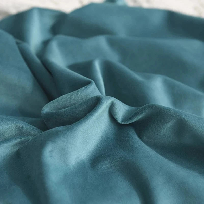 Housse de coussin en velours bleu, douce et élégante, drapée sur un canapé moderne