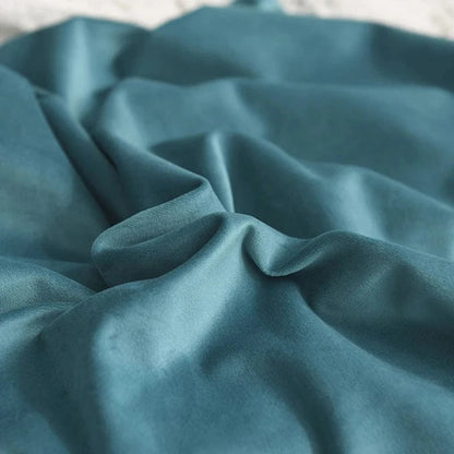 Housse de coussin en velours bleu, douce et élégante, drapée sur un canapé moderne