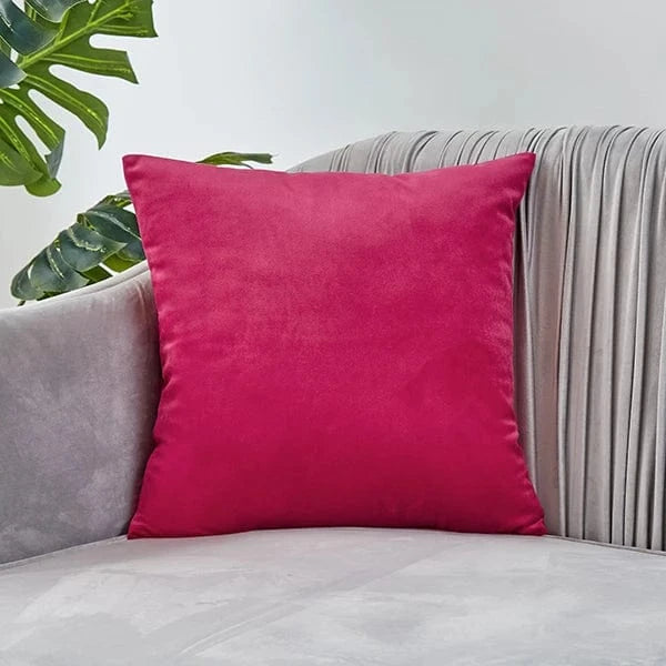 Coussin décoratif en velours fuchsia posé sur un canapé gris, ajoutant une touche de couleur élégante