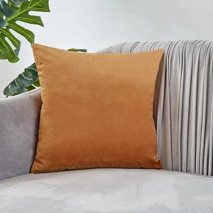 Coussin déco en velours orange posé sur un canapé gris, ajoutant une touche d'élégance à la pièce