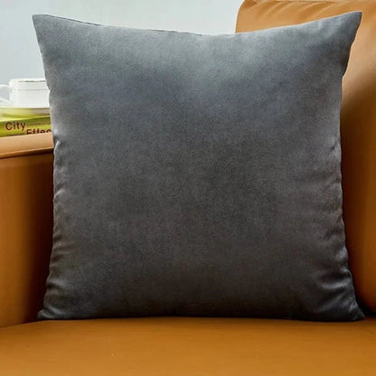 Coussin déco en velours gris posé sur un canapé marron, ajoutant une touche d'élégance à la décoration intérieure