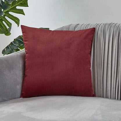 Coussin décoratif en velours rouge posé sur un canapé gris, ajoutant une touche d'élégance à la décoration intérieure