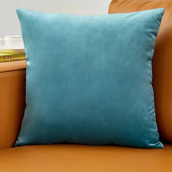 Coussin déco en velours bleu posé sur un canapé marron, ajoutant une touche d'élégance à la pièce