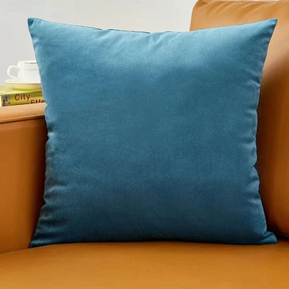 Coussin déco en velours bleu posé sur un canapé marron, ajoutant une touche d'élégance à la pièce