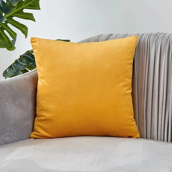 Coussin déco en velours jaune posé sur un canapé gris, apportant une touche élégante et chaleureuse au salon