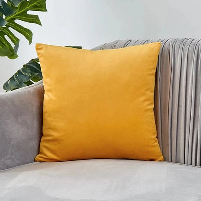 Coussin déco en velours jaune posé sur un canapé gris, apportant une touche élégante et chaleureuse au salon