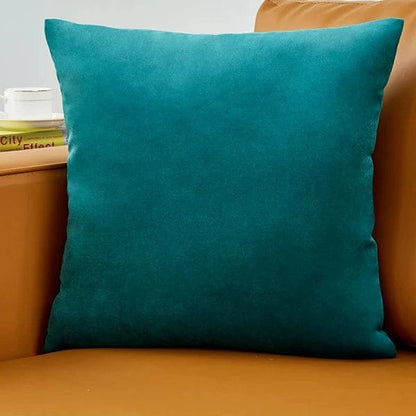 Coussin décoratif en velours turquoise posé sur un canapé en cuir marron, ajoutant une touche d'élégance