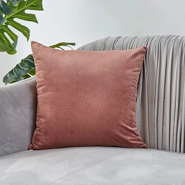 Coussin déco en velours rose posé sur un canapé gris, ajoutant une touche d'élégance à la décoration intérieure