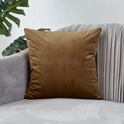 Coussin déco en velours marron posé sur un canapé gris, ajoutant élégance et confort à la décoration intérieure