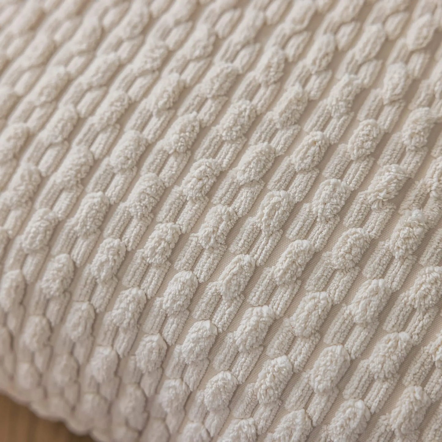 Housse de coussin décoratif beige avec un motif texturé sur un canapé moderne et élégant