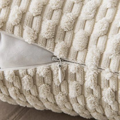 Housse de coussin décoratif beige avec texture en relief, zippée, posée sur un canapé en tissu neutre