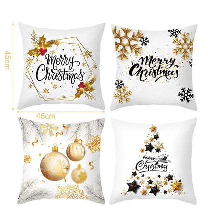 Quatre coussins décoratifs aux motifs de Noël, avec des couleurs blanches, dorées et des illustrations festives, sur un canapé