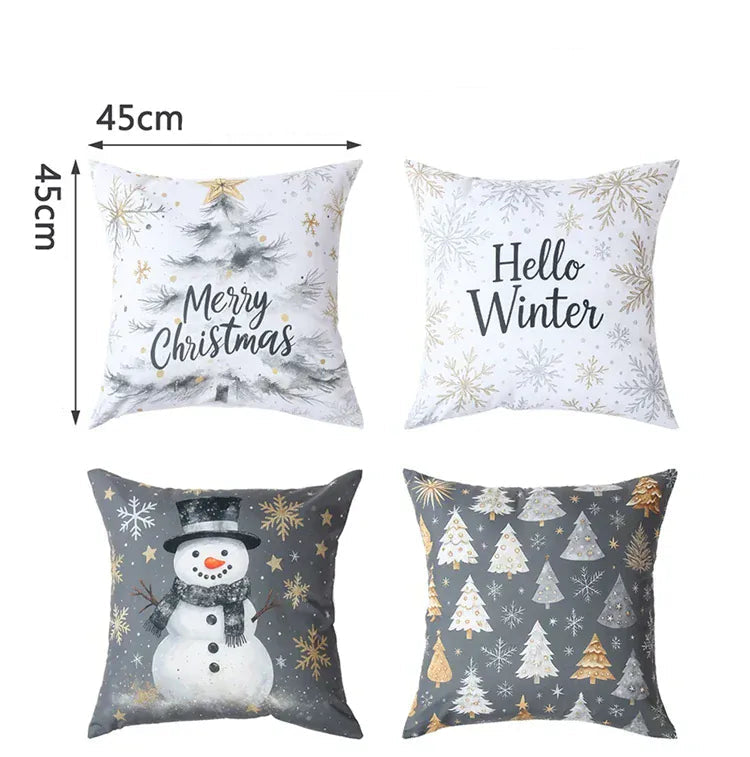 Quatre housses de coussin décoratives avec motifs de Noël, couleurs blanches, grises et dorées, sur un canapé