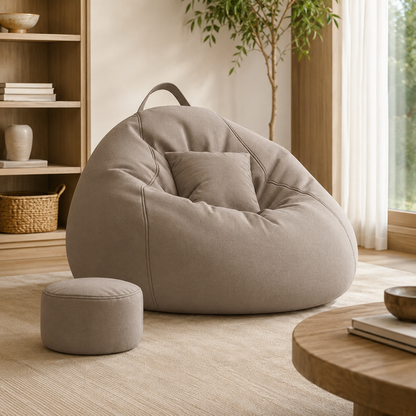 Pouf salon géant gris avec repose-pieds assorti installé dans un coin détente lumineux
