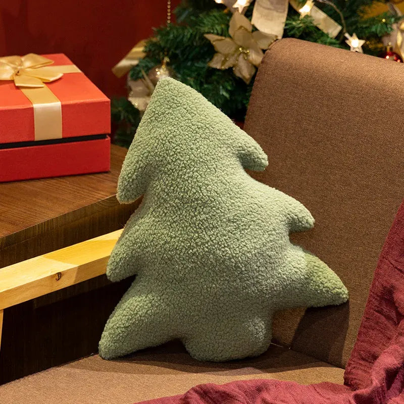 Coussin en forme de sapin de Noël vert, posé sur un canapé marron, décoré pour les fêtes