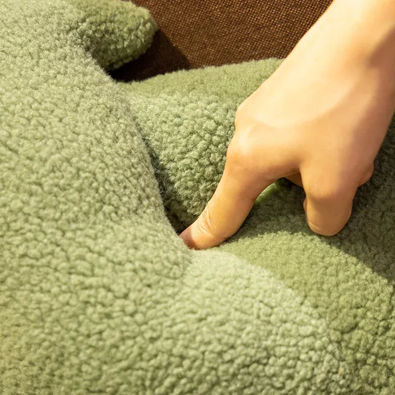 Coussin décoratif en forme de sapin de Noël, en tissu vert doux, posé sur un canapé marron