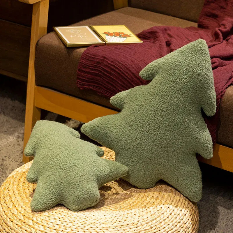 Deux coussins en forme de sapin, en tissu vert doux, décorent un canapé en bois et une couverture bordeaux