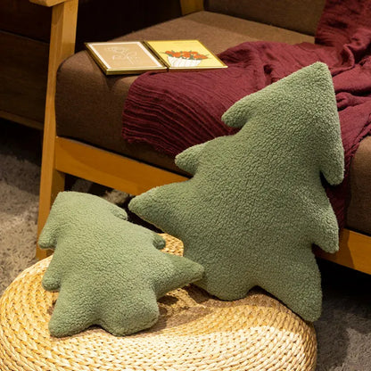 Deux coussins en forme de sapin, en tissu vert doux, décorent un canapé en bois et une couverture bordeaux